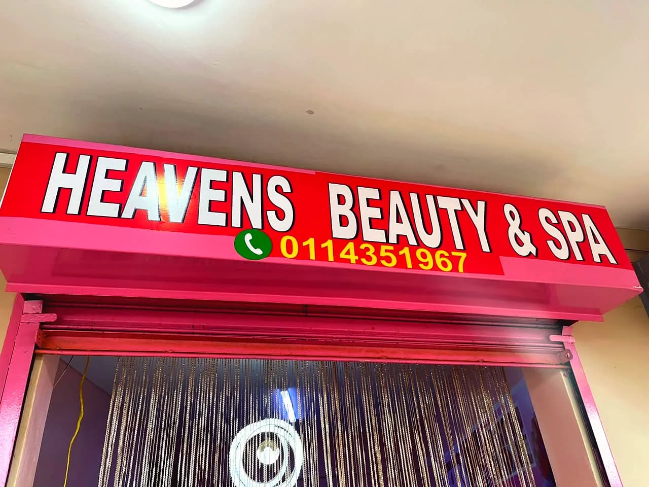 Pink Heavens Beauty & Spa sign above the salon entrance with a beaded door curtain