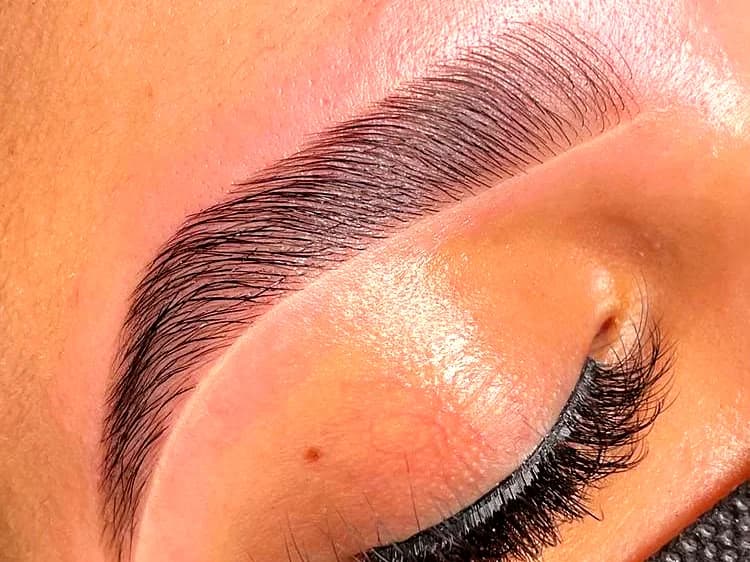 Close-up of a full, neatly shaped brow above a lash-extended closed eye